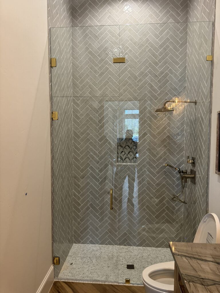 Modern glass shower with herringbone tiles